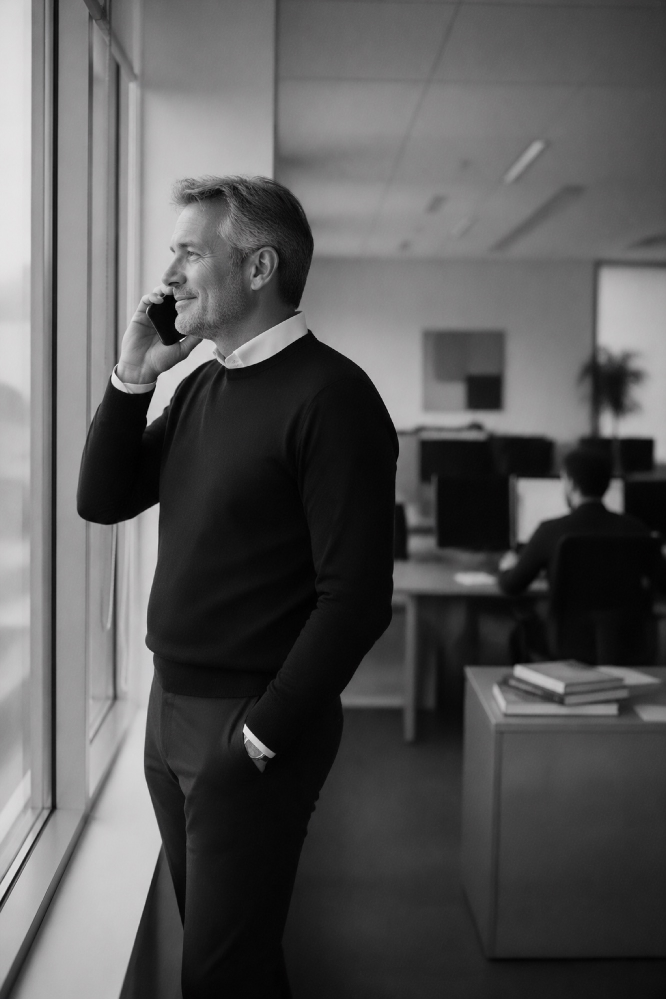 Mand i telefon ved vinduet paa kontoret